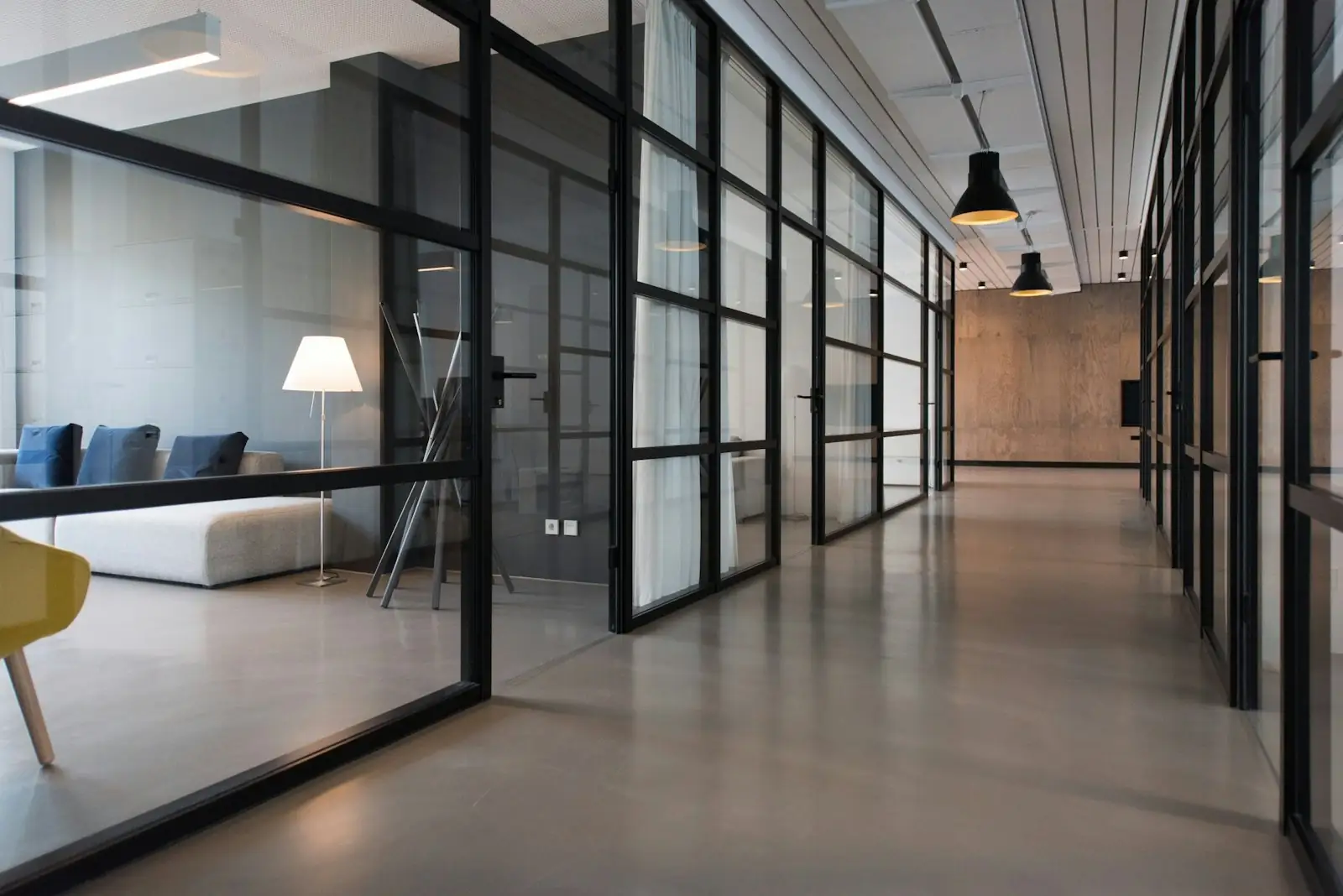 A corridor of glass-walled offices in natural light